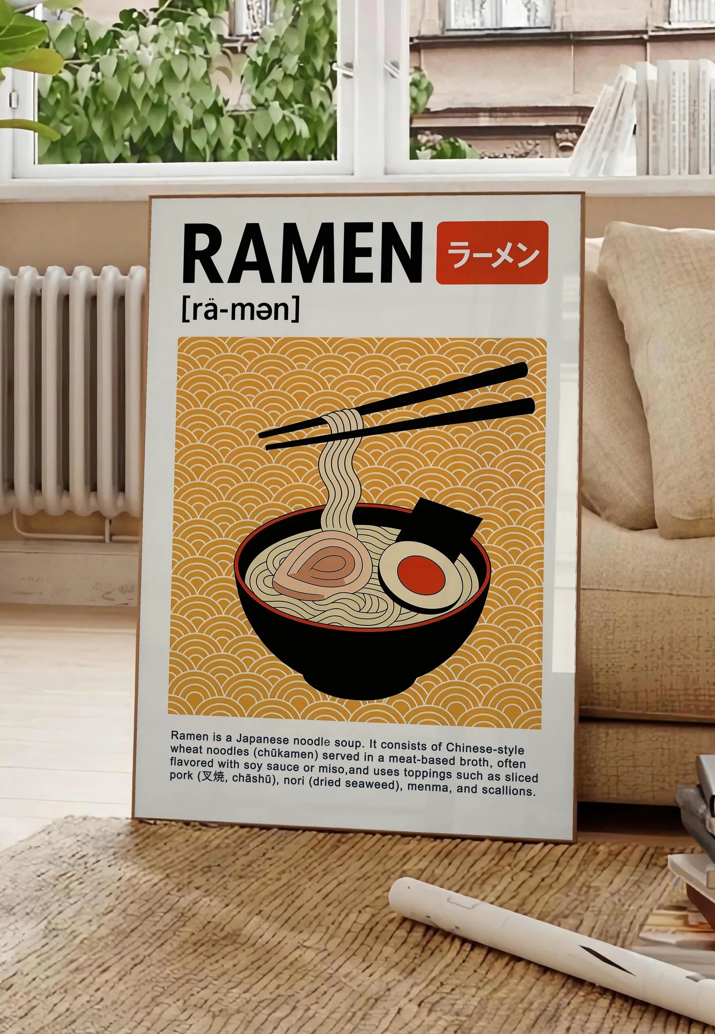 Poster affiche cuisine ramen japonais, posee au sol dans un salon parisien, devant une grande fenetre donnant sur un immeuble haussmannien, entre un ficus et un canape creme