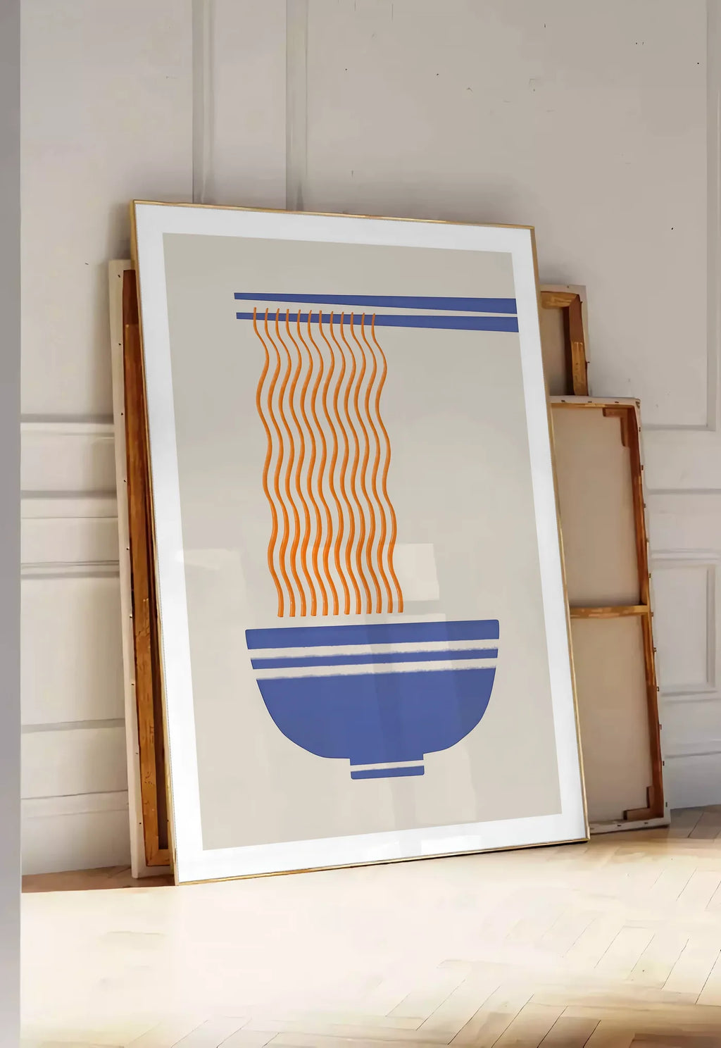 Tirage encadrable affiche cuisine ramen, posee au sol dans une entree lumineuse, contre un mur a panneaux blancs, a cote de chassis en bois empiles