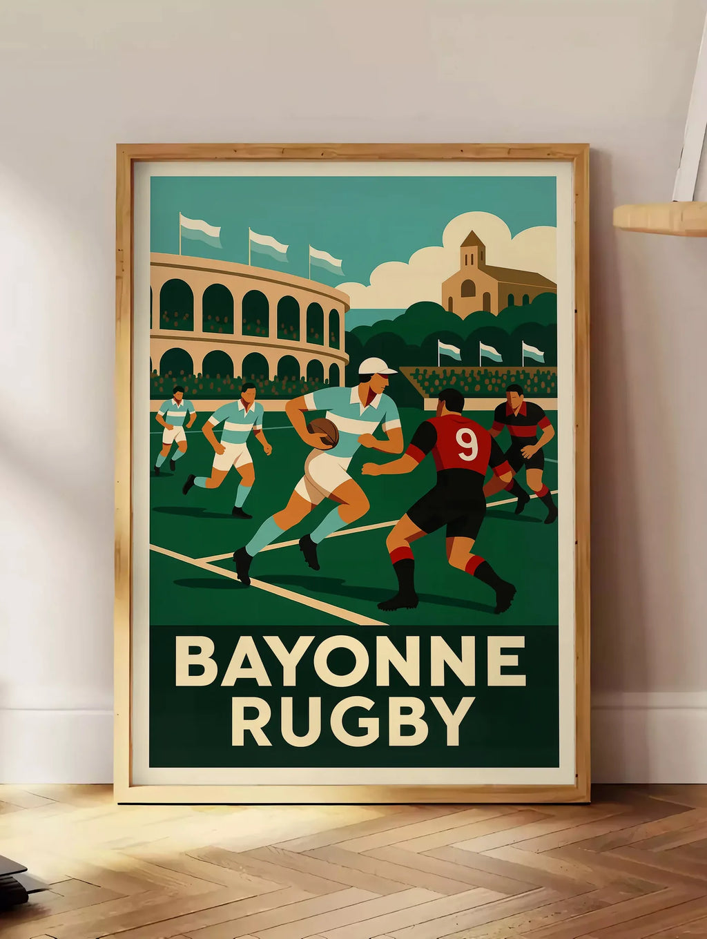 Estampe joueurs de rugby en maillots rayés, posee au sol dans un coin salon, sur un parquet a chevrons, pres d'une table d'appoint en chene chargee de livres