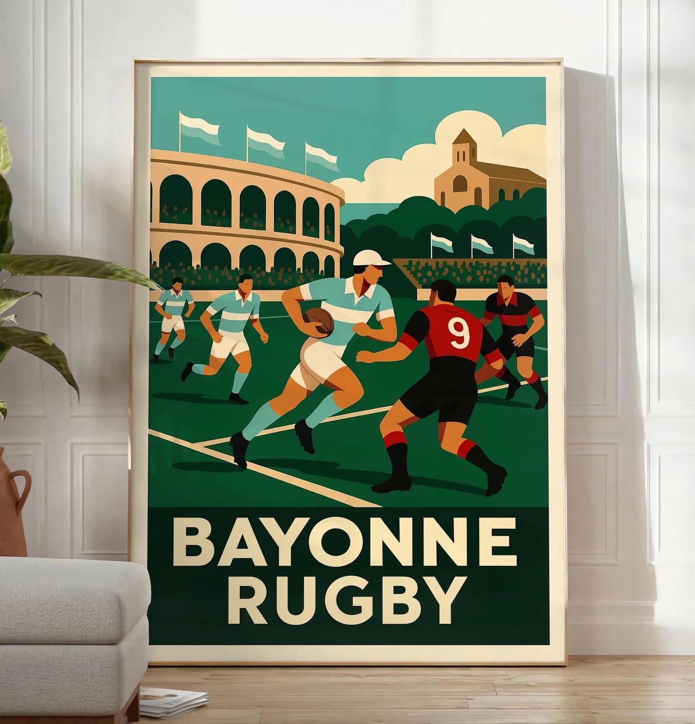 Reproduction joueurs de rugby en maillots rayés, posee au sol dans un salon minimaliste clair, a cote d'un canape beige et d'une plante verte, sur un parquet clair