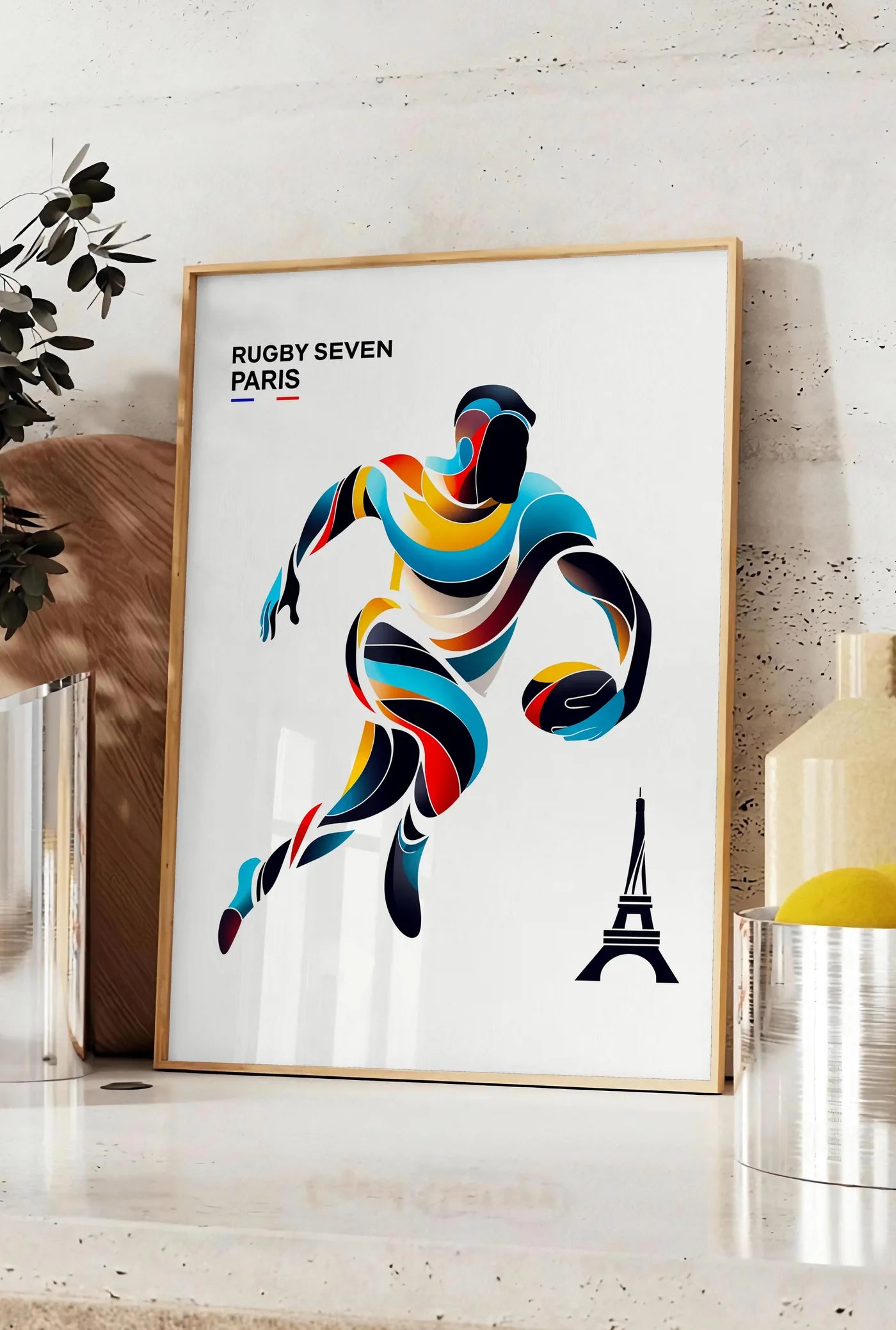 Affiche affiche rugby Paris, posee sur un plan de travail de cuisine en pierre claire, entre une branche d'eucalyptus en vase et un bocal de citrons
