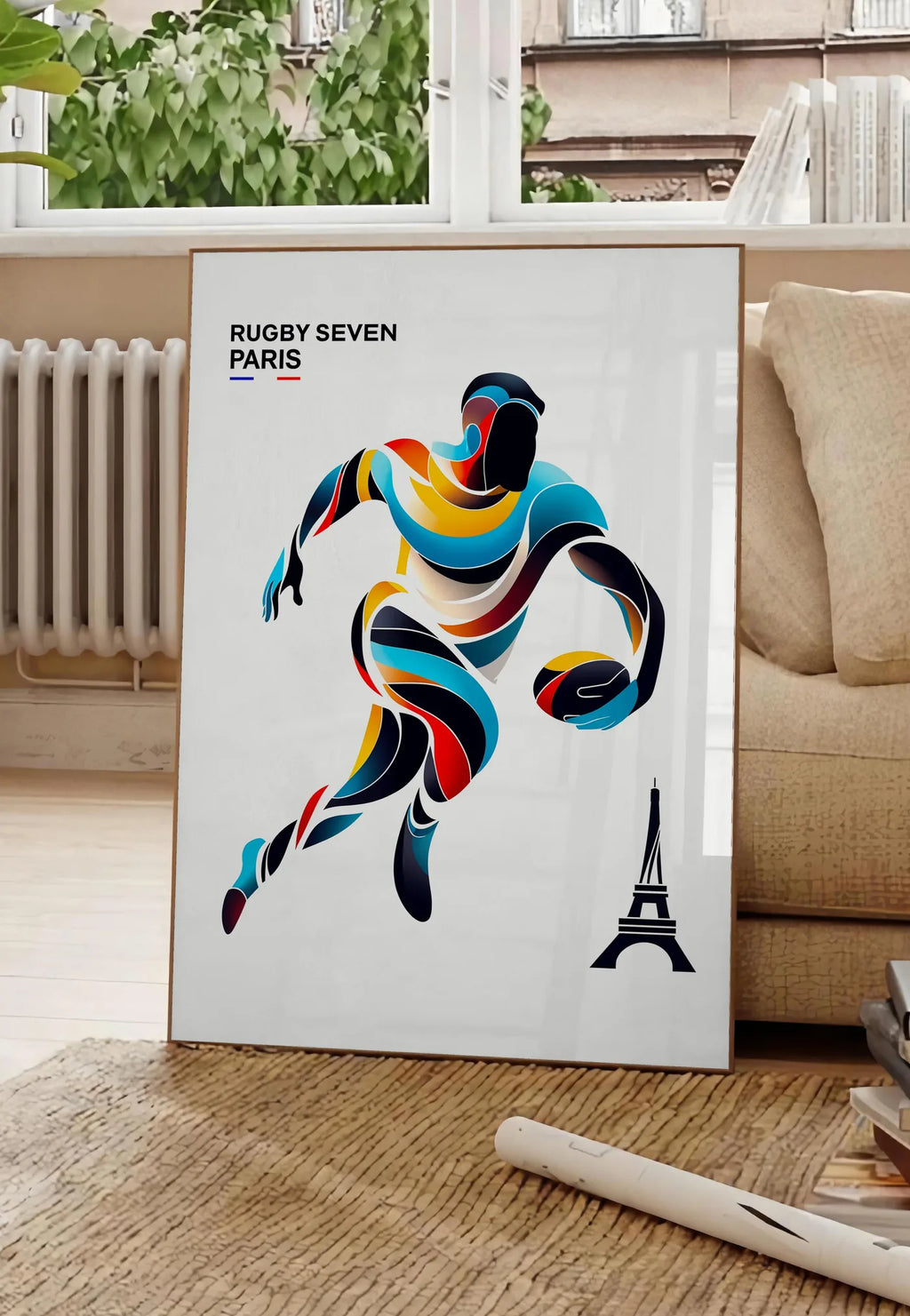 Poster affiche rugby Paris, posee au sol dans un salon parisien, devant une grande fenetre donnant sur un immeuble haussmannien, entre un ficus et un canape creme