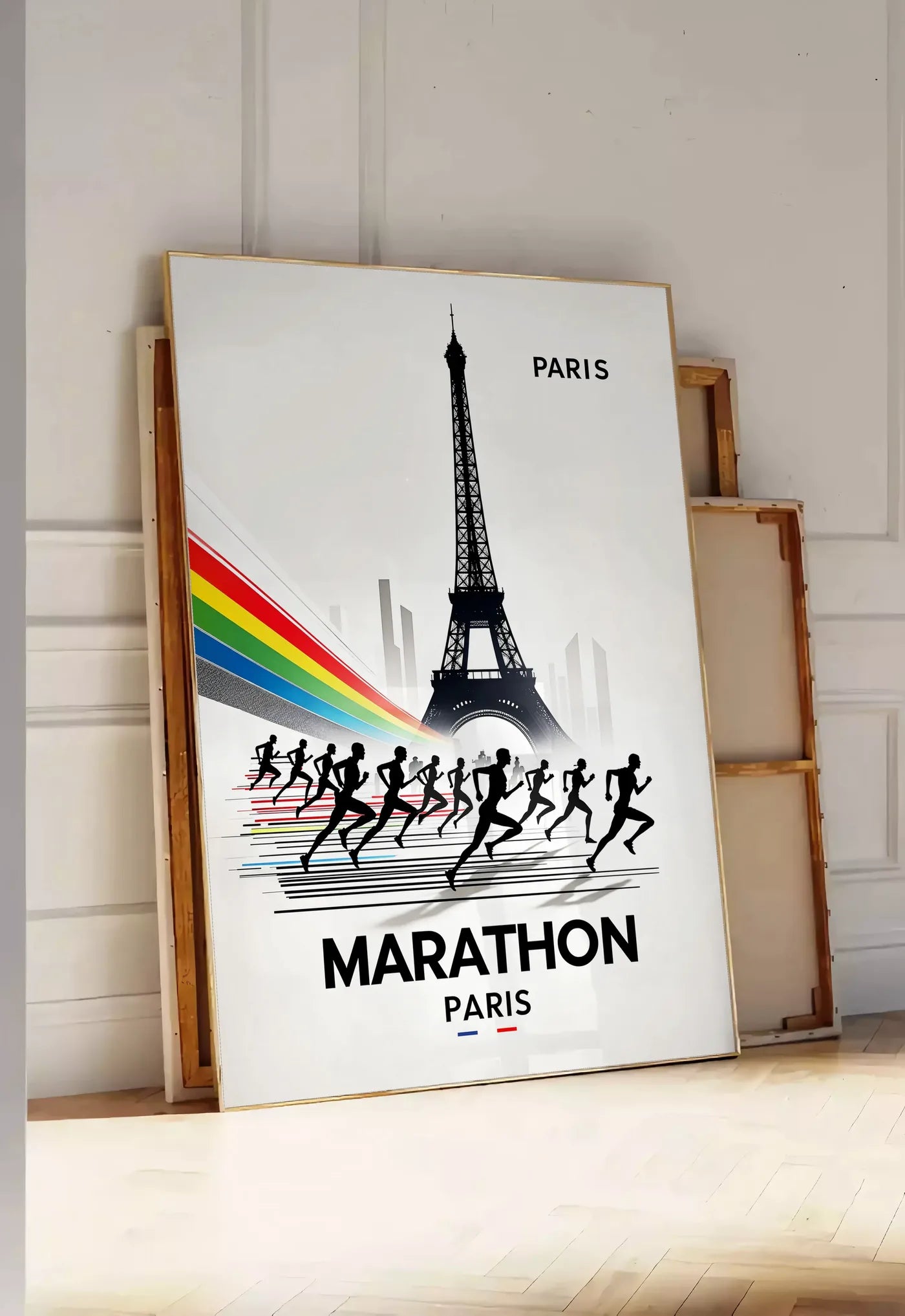 Tirage encadrable silhouettes de coureurs devant la Tour Eiffel, posee au sol dans une entree lumineuse, contre un mur a panneaux blancs, a cote de chassis en bois empiles
