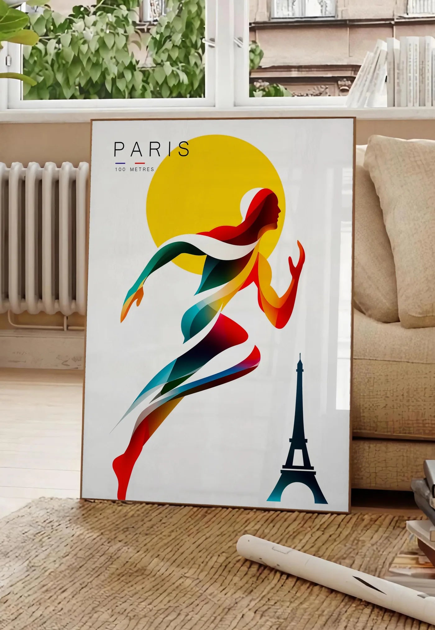 Poster affiche Paris 100 metres, posee au sol dans un salon parisien, devant une grande fenetre donnant sur un immeuble haussmannien, entre un ficus et un canape creme