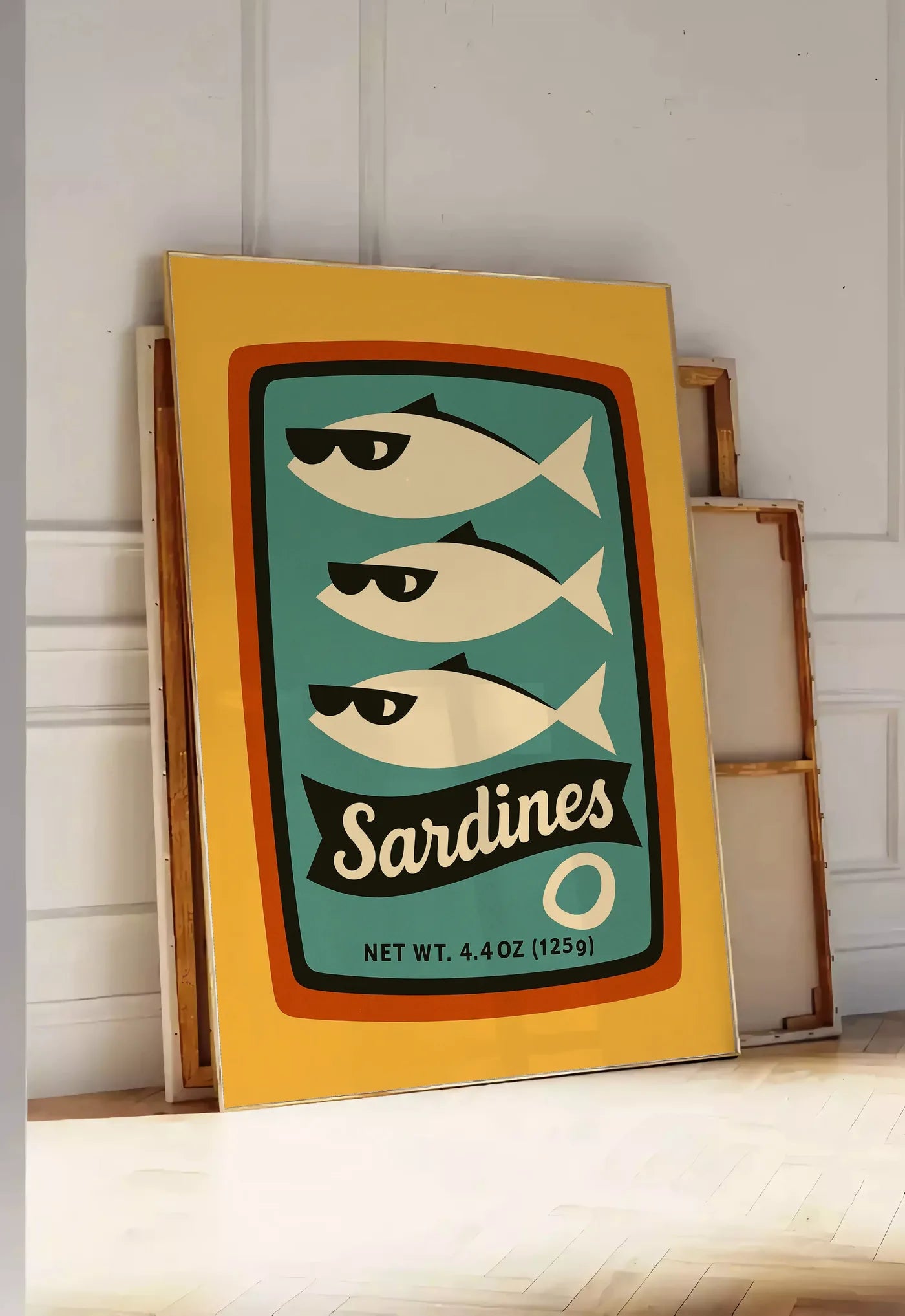 Tirage encadrable affiche cuisine sardines, posee au sol dans une entree lumineuse, contre un mur a panneaux blancs, a cote de chassis en bois empiles