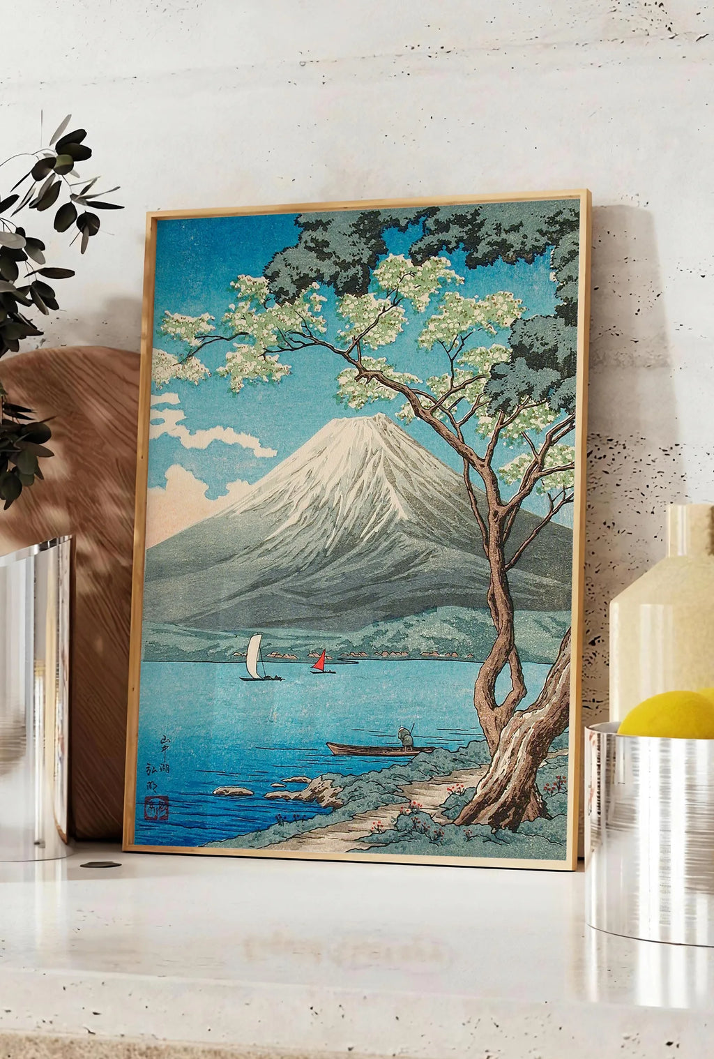 Affiche affiche Mont Fuji estampe, posee sur un plan de travail de cuisine en pierre claire, entre une branche d'eucalyptus en vase et un bocal de citrons