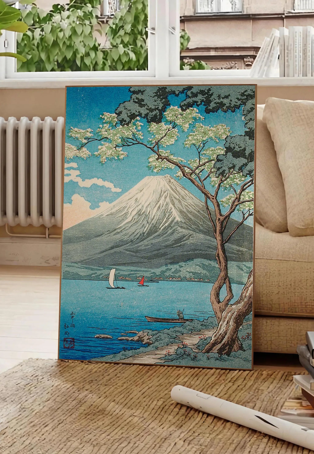 Poster affiche Mont Fuji estampe, posee au sol dans un salon parisien, devant une grande fenetre donnant sur un immeuble haussmannien, entre un ficus et un canape creme