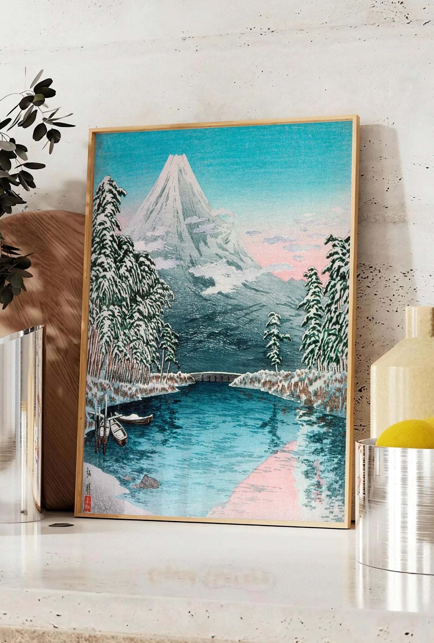 Affiche affiche Mont Fuji estampe, posee sur un plan de travail de cuisine en pierre claire, entre une branche d'eucalyptus en vase et un bocal de citrons