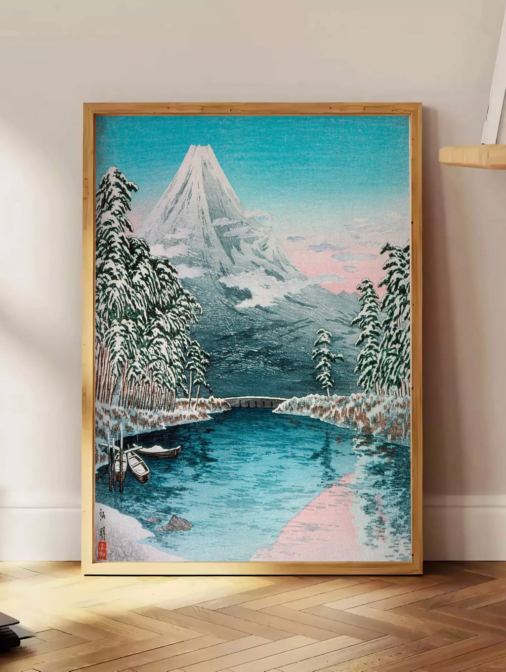 Estampe affiche Mont Fuji estampe, posee au sol dans un coin salon, sur un parquet a chevrons, pres d'une table d'appoint en chene chargee de livres