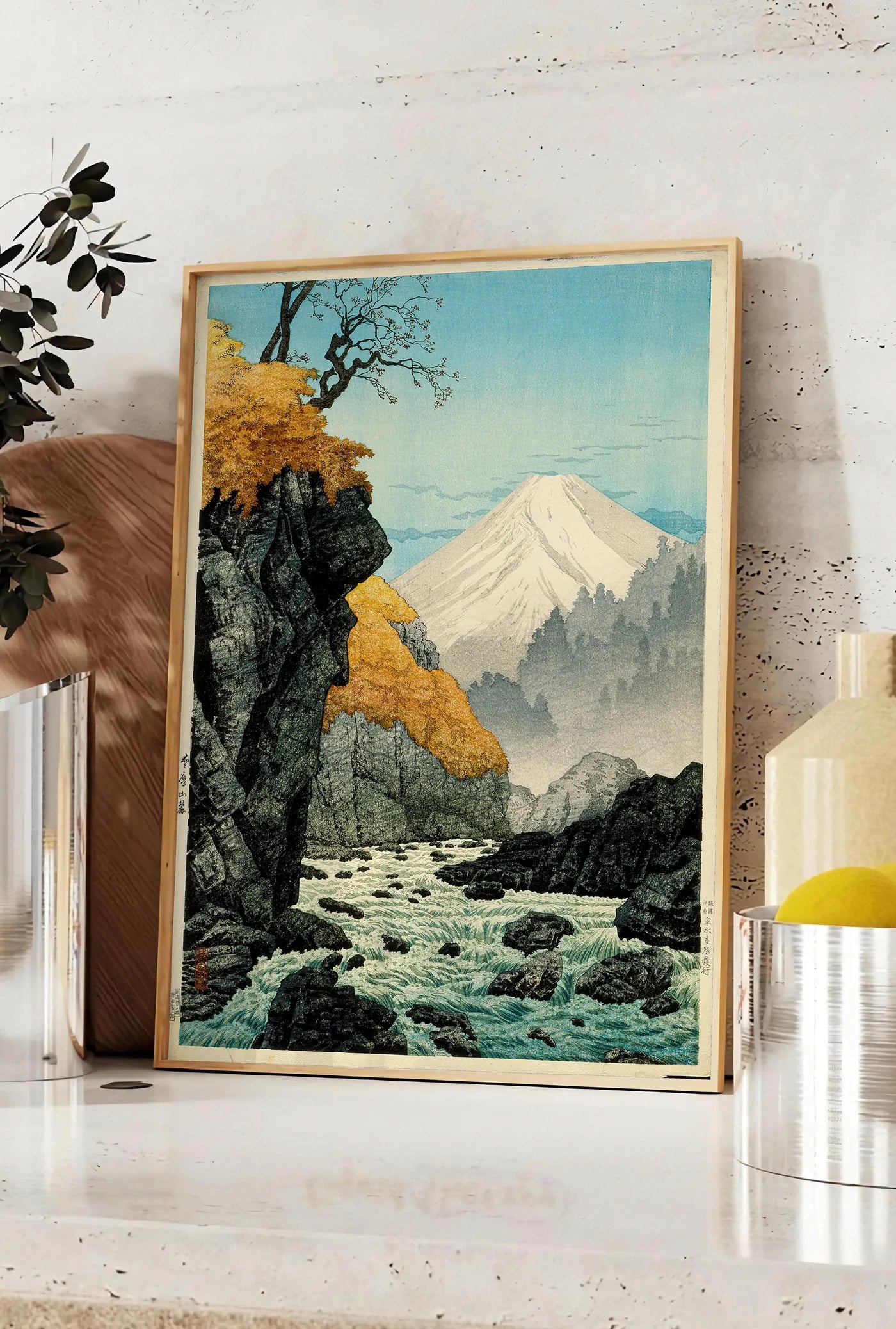 Affiche affiche Mont Fuji estampe, posee sur un plan de travail de cuisine en pierre claire, entre une branche d'eucalyptus en vase et un bocal de citrons