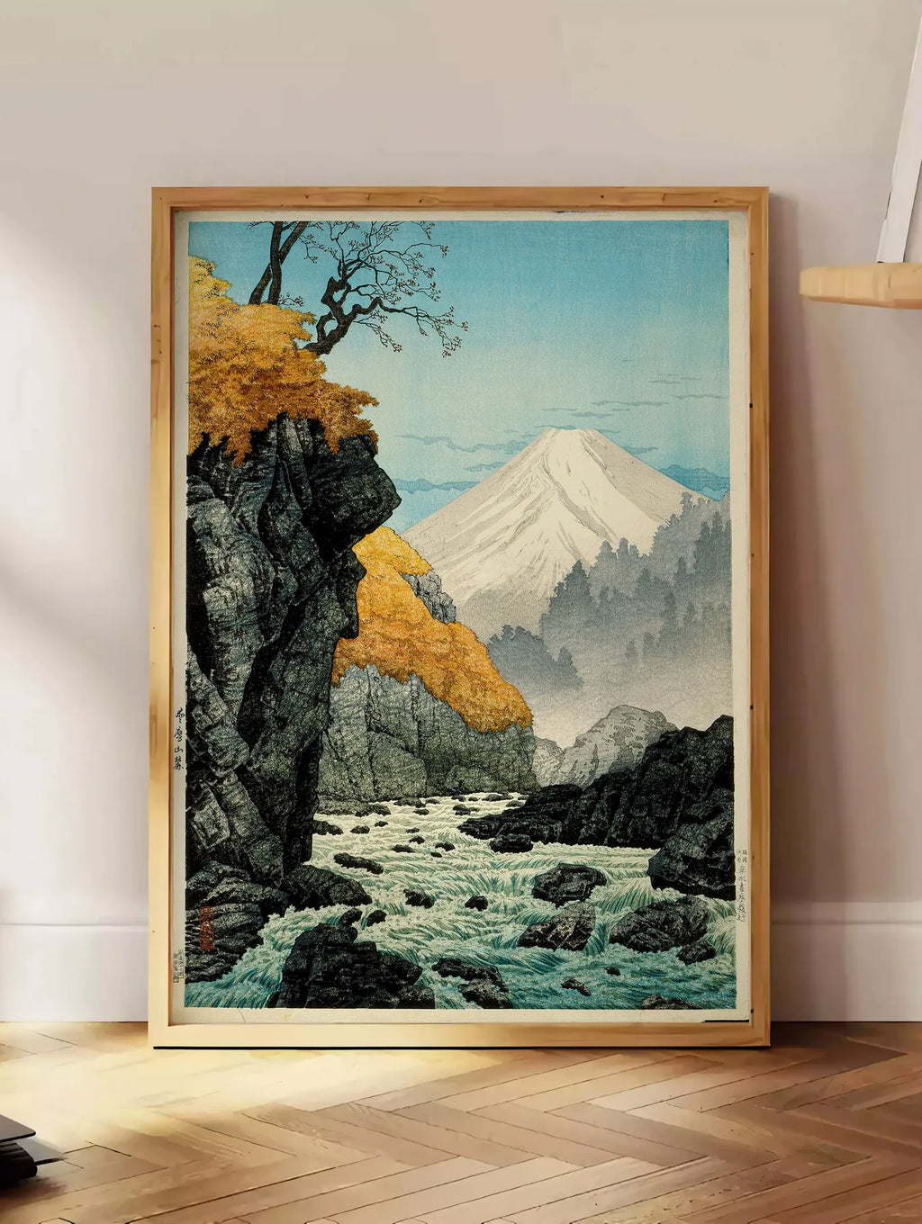 Estampe affiche Mont Fuji estampe, posee au sol dans un coin salon, sur un parquet a chevrons, pres d'une table d'appoint en chene chargee de livres