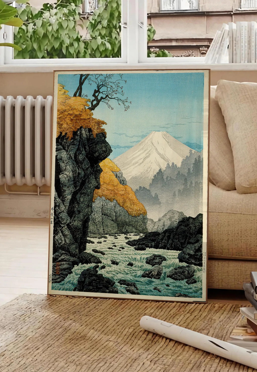 Poster affiche Mont Fuji estampe, posee au sol dans un salon parisien, devant une grande fenetre donnant sur un immeuble haussmannien, entre un ficus et un canape creme
