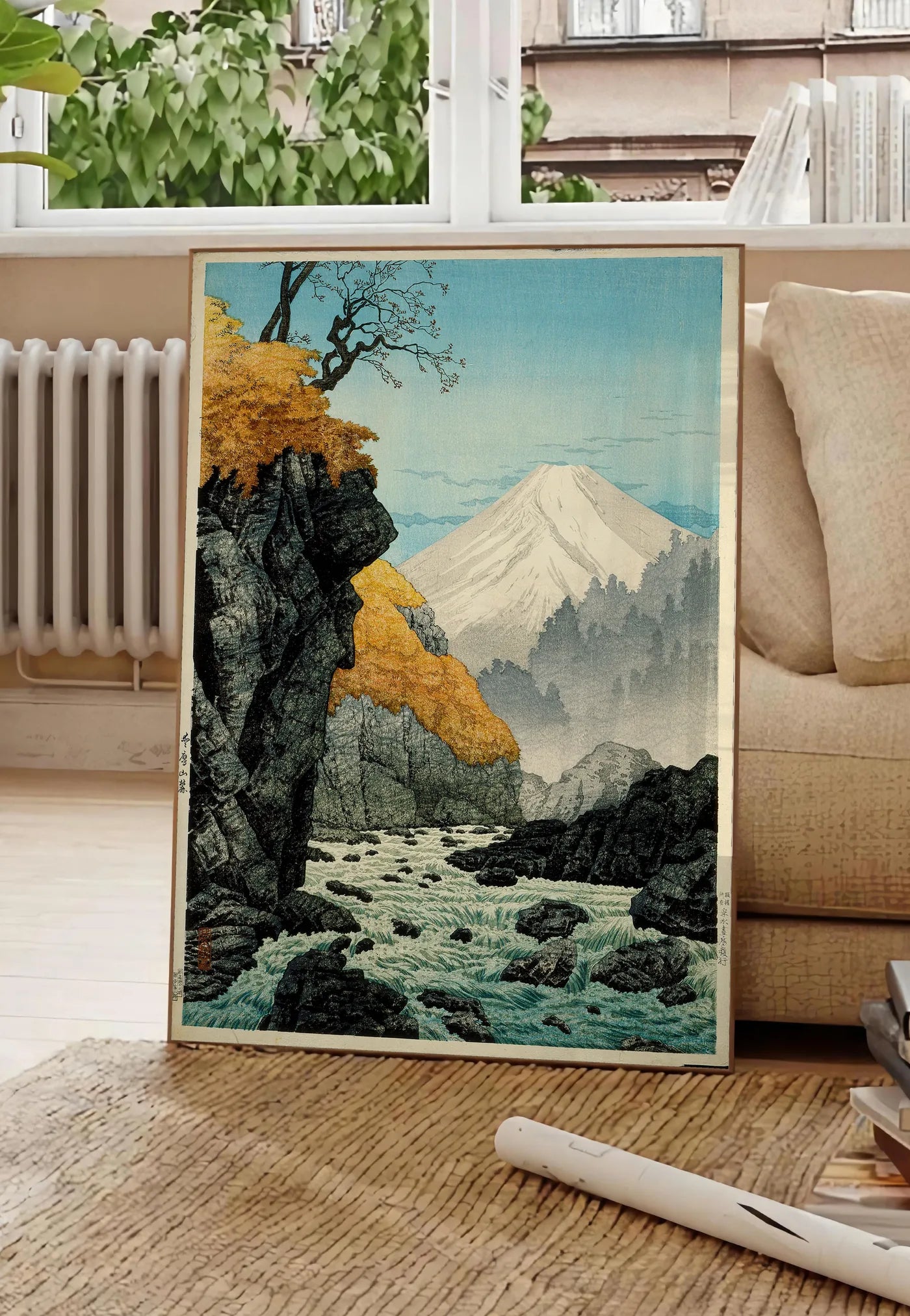 Poster affiche Mont Fuji estampe, posee au sol dans un salon parisien, devant une grande fenetre donnant sur un immeuble haussmannien, entre un ficus et un canape creme