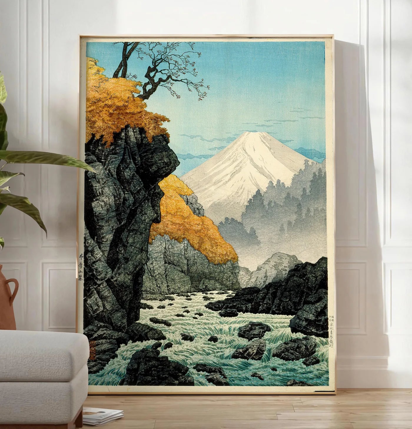 Reproduction affiche Mont Fuji estampe, posee au sol dans un salon minimaliste clair, a cote d'un canape beige et d'une plante verte, sur un parquet clair