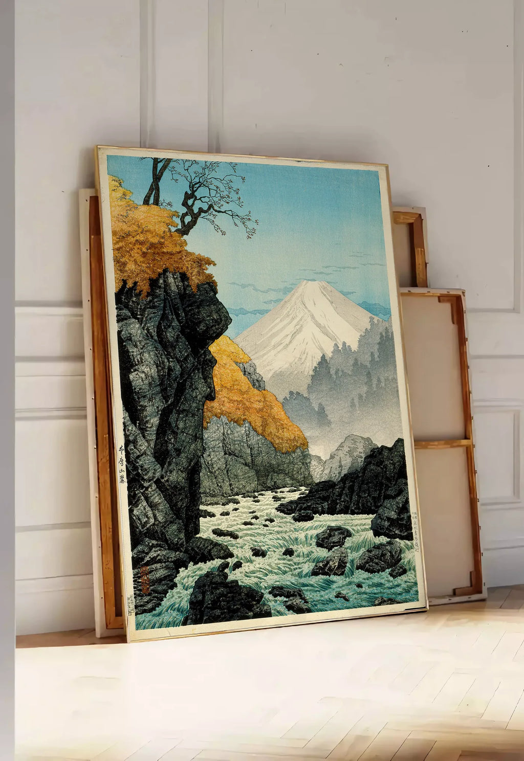 Tirage encadrable affiche Mont Fuji estampe, posee au sol dans une entree lumineuse, contre un mur a panneaux blancs, a cote de chassis en bois empiles