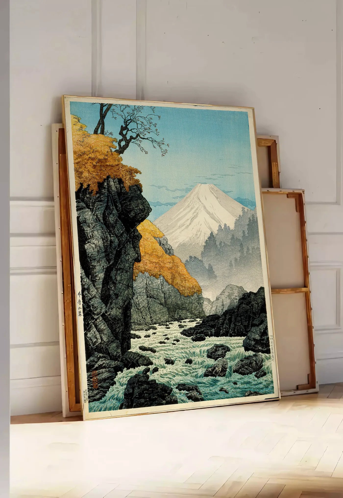 Tirage encadrable affiche Mont Fuji estampe, posee au sol dans une entree lumineuse, contre un mur a panneaux blancs, a cote de chassis en bois empiles