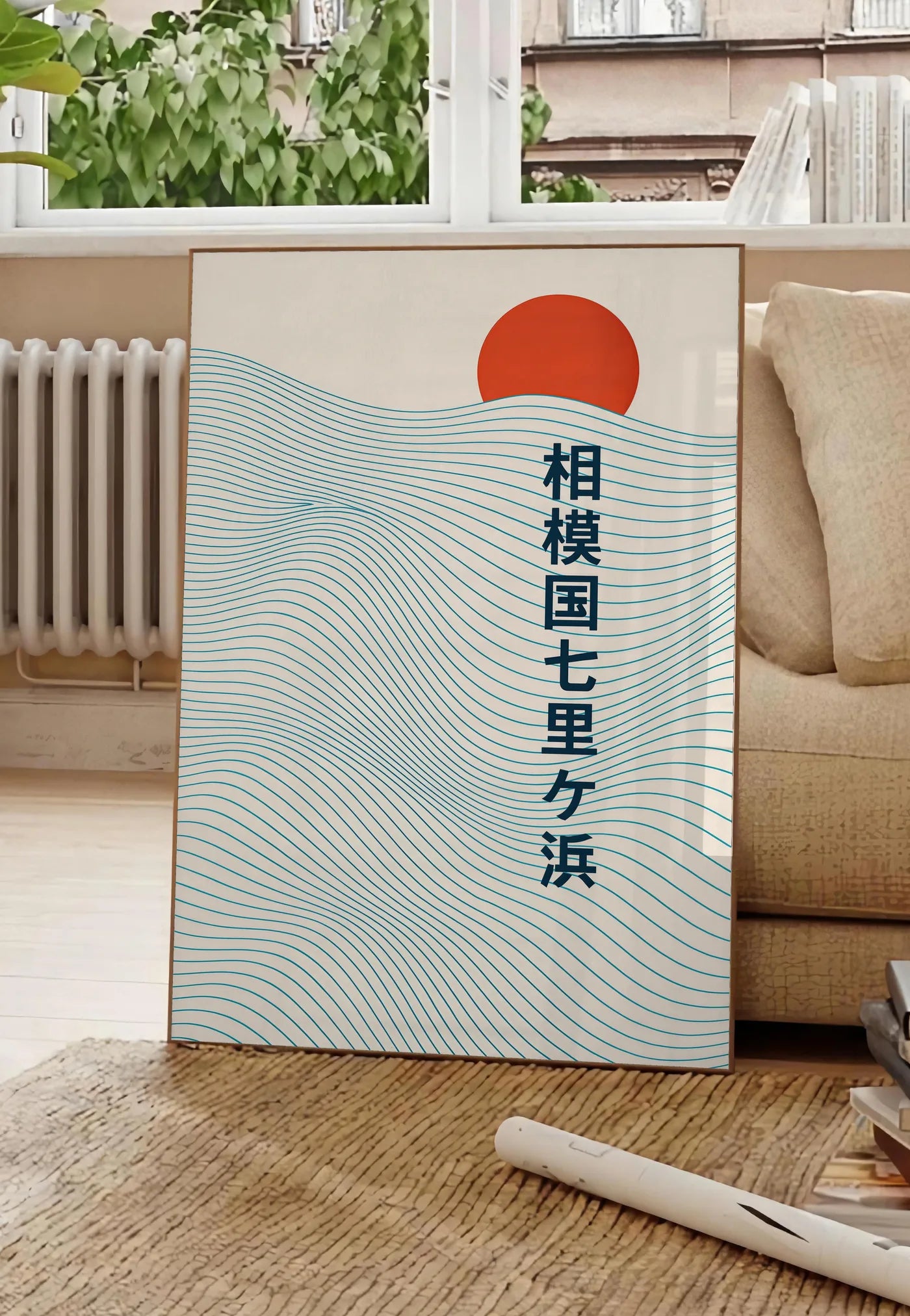 Poster affiche soleil rouge levant au-dessus de vagues japonaises au trait, posee au sol dans un salon parisien, devant une grande fenetre donnant sur un immeuble haussmannien, entre un ficus et un canape creme