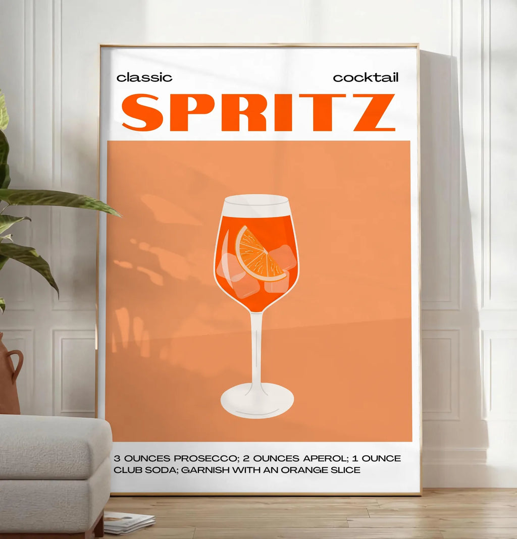 Reproduction affiche cocktail Spritz, posee au sol dans un salon minimaliste clair, a cote d'un canape beige et d'une plante verte, sur un parquet clair