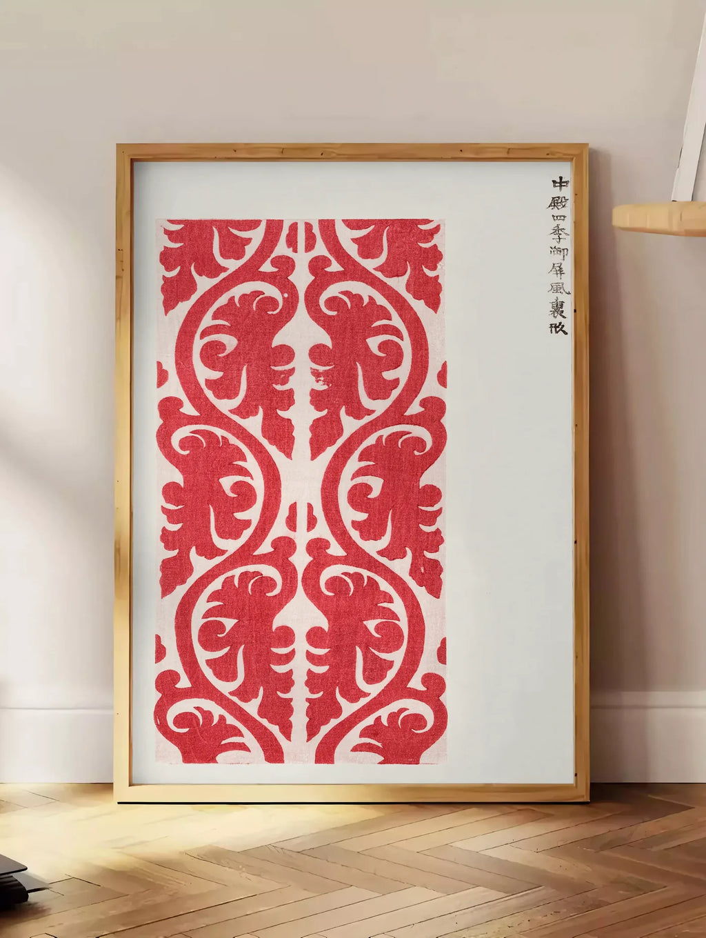 Estampe affiche motif rouge de feuillage de Taguchi Tomoki, posee au sol dans un coin salon, sur un parquet a chevrons, pres d'une table d'appoint en chene chargee de livres