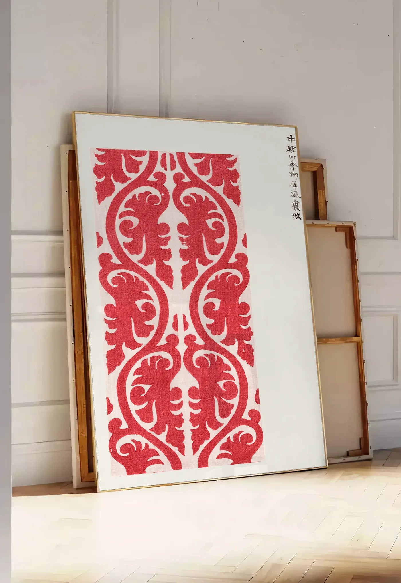 Tirage encadrable affiche motif rouge de feuillage de Taguchi Tomoki, posee au sol dans une entree lumineuse, contre un mur a panneaux blancs, a cote de chassis en bois empiles