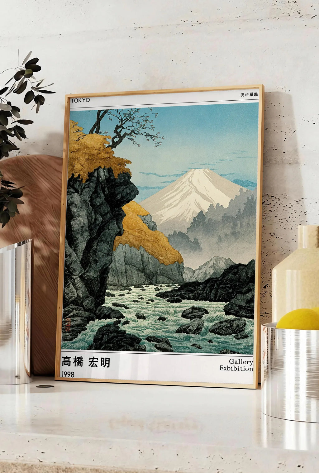 Affiche affiche mont Fuji Takahashi Hiroaki, posee sur un plan de travail de cuisine en pierre claire, entre une branche d'eucalyptus en vase et un bocal de citrons