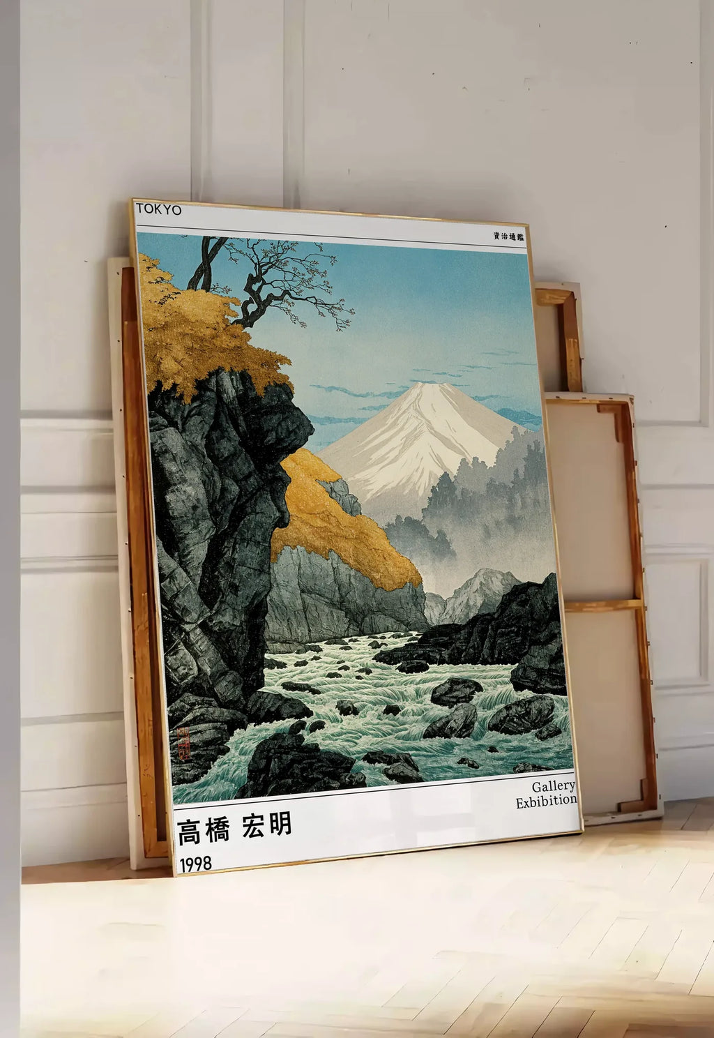 Tirage encadrable affiche mont Fuji Takahashi Hiroaki, posee au sol dans une entree lumineuse, contre un mur a panneaux blancs, a cote de chassis en bois empiles