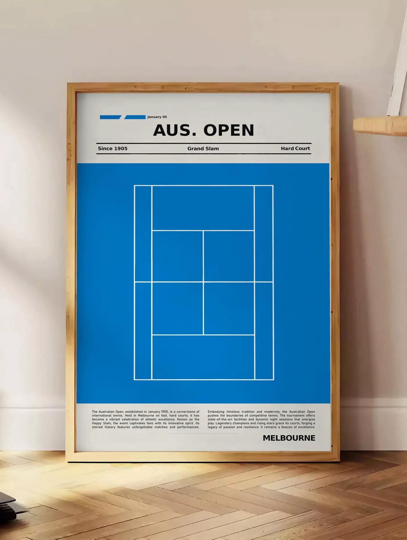 Estampe court de tennis stylisé, posee au sol dans un coin salon, sur un parquet a chevrons, pres d'une table d'appoint en chene chargee de livres