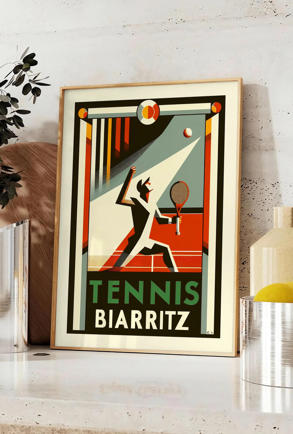 Affiche silhouette de joueur de tennis stylisé frappant une balle, posee sur un plan de travail de cuisine en pierre claire, entre une branche d'eucalyptus en vase et un bocal de citrons