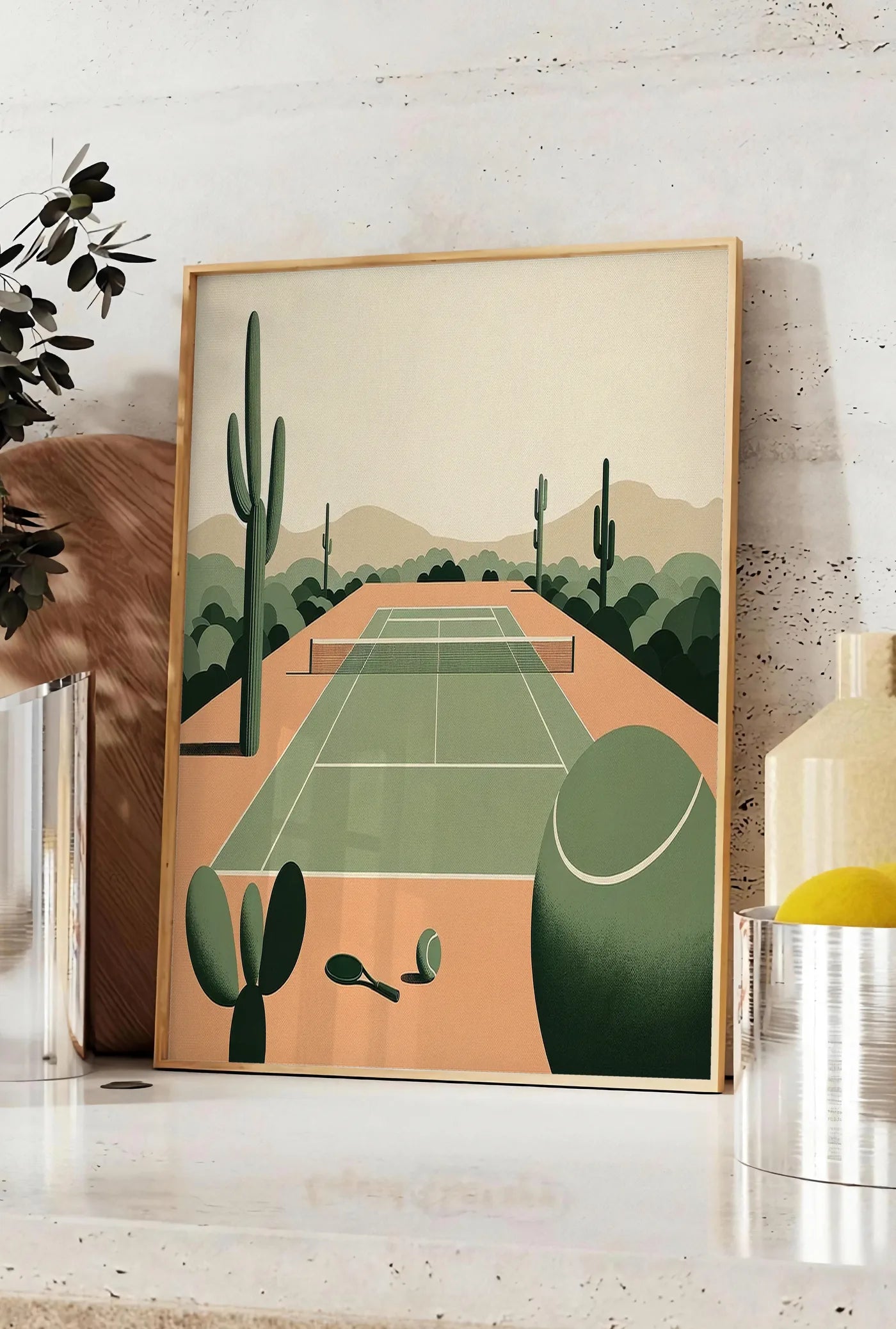 Affiche affiche tennis desert, posee sur un plan de travail de cuisine en pierre claire, entre une branche d'eucalyptus en vase et un bocal de citrons