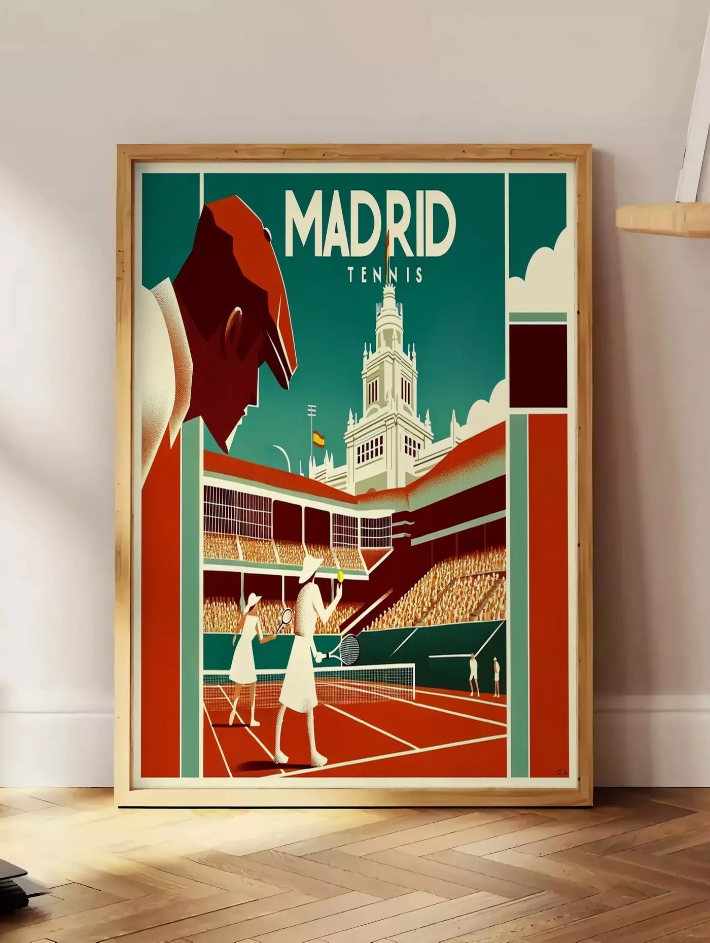 Estampe affiche tennis Madrid art deco, posee au sol dans un coin salon, sur un parquet a chevrons, pres d'une table d'appoint en chene chargee de livres