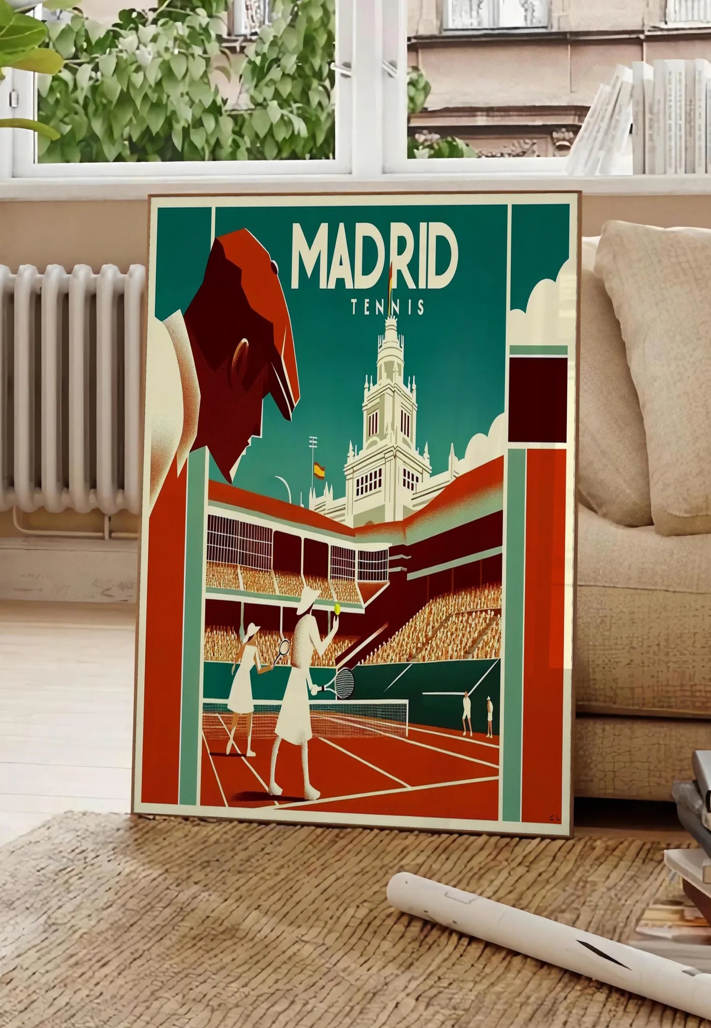 Poster affiche tennis Madrid art deco, posee au sol dans un salon parisien, devant une grande fenetre donnant sur un immeuble haussmannien, entre un ficus et un canape creme