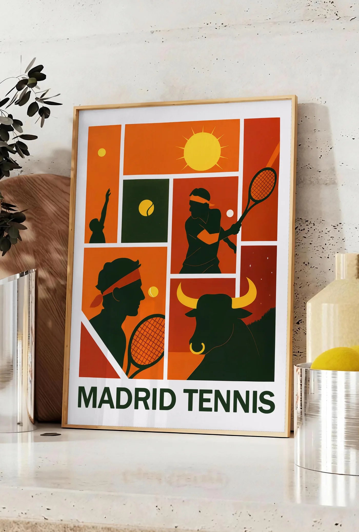 Affiche joueur de tennis au service et taureau, posee sur un plan de travail de cuisine en pierre claire, entre une branche d'eucalyptus en vase et un bocal de citrons