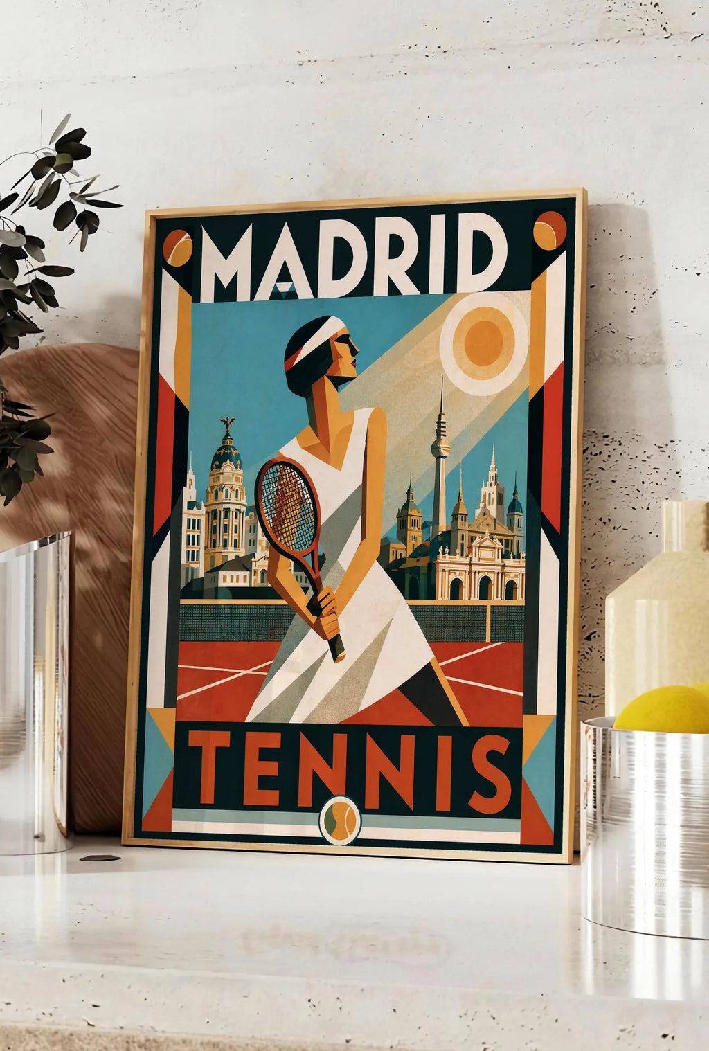 Affiche affiche tennis Madrid art deco nocturne, posee sur un plan de travail de cuisine en pierre claire, entre une branche d'eucalyptus en vase et un bocal de citrons