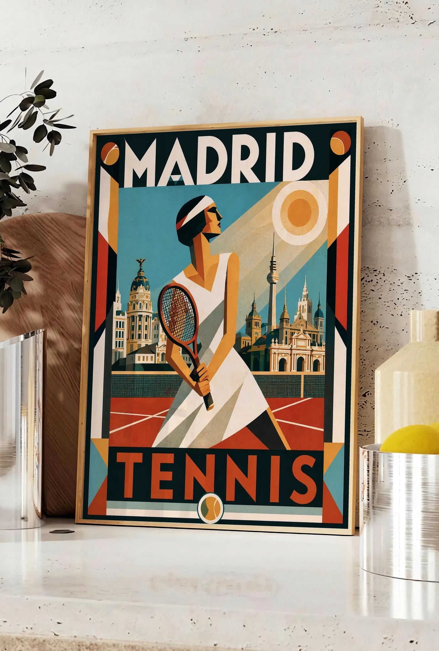 Affiche affiche tennis Madrid art deco nocturne, posee sur un plan de travail de cuisine en pierre claire, entre une branche d'eucalyptus en vase et un bocal de citrons
