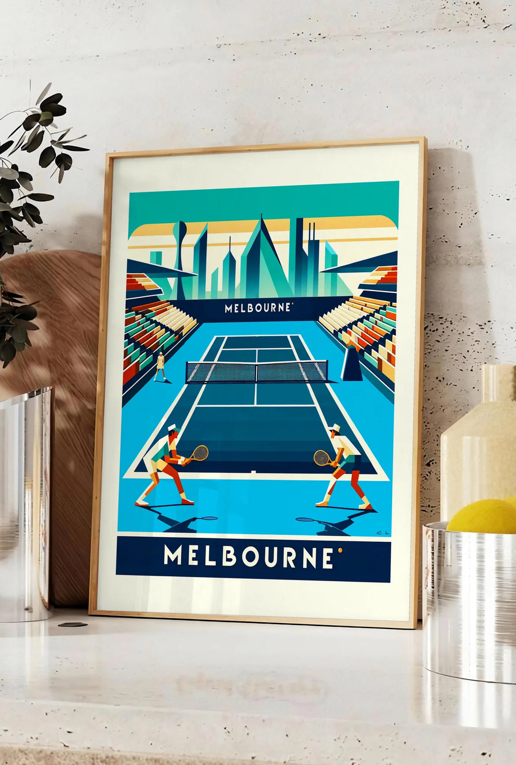 Affiche deux joueurs de tennis sur court bleu, posee sur un plan de travail de cuisine en pierre claire, entre une branche d'eucalyptus en vase et un bocal de citrons