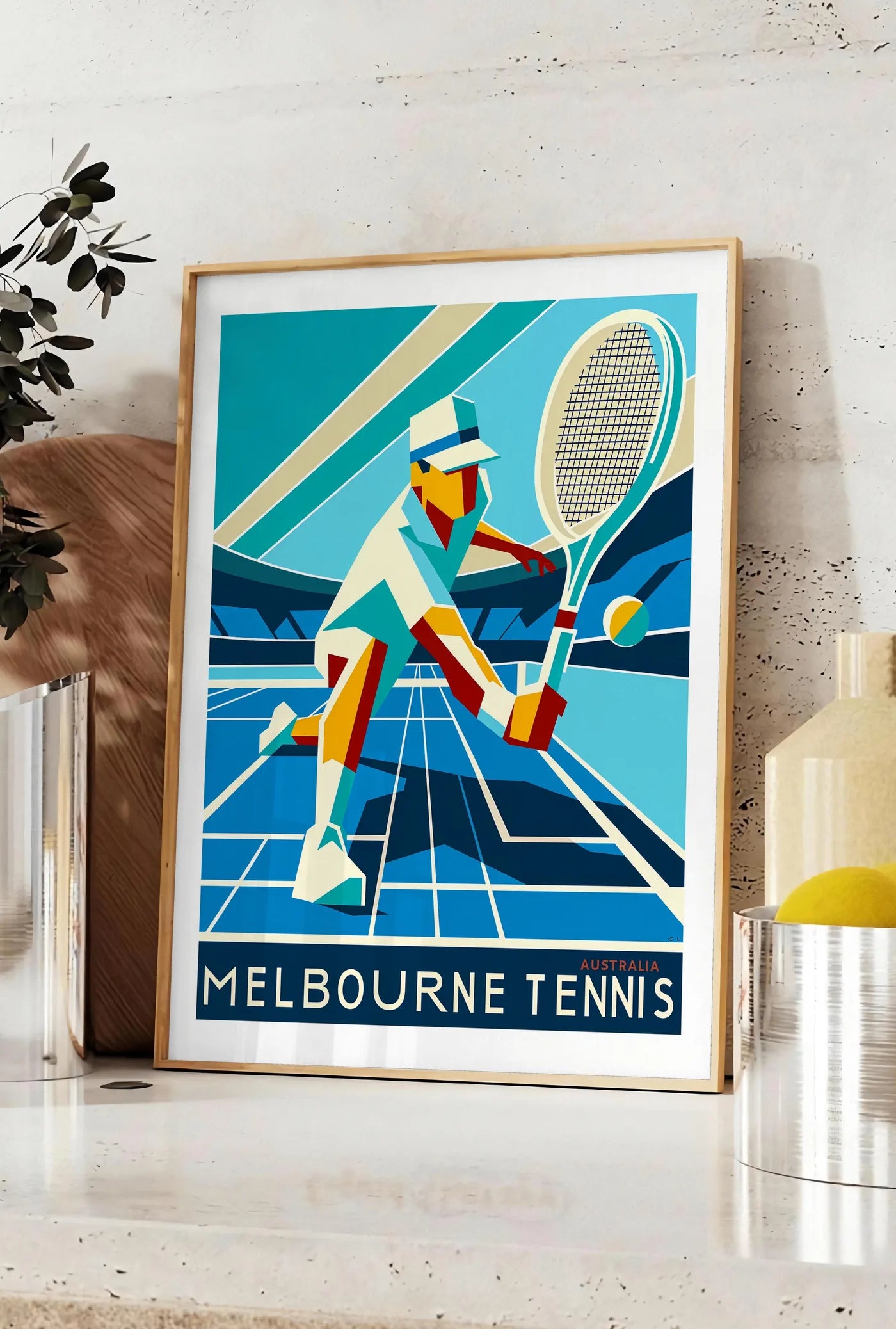 Affiche affiche tennis Melbourne Art Deco, posee sur un plan de travail de cuisine en pierre claire, entre une branche d'eucalyptus en vase et un bocal de citrons