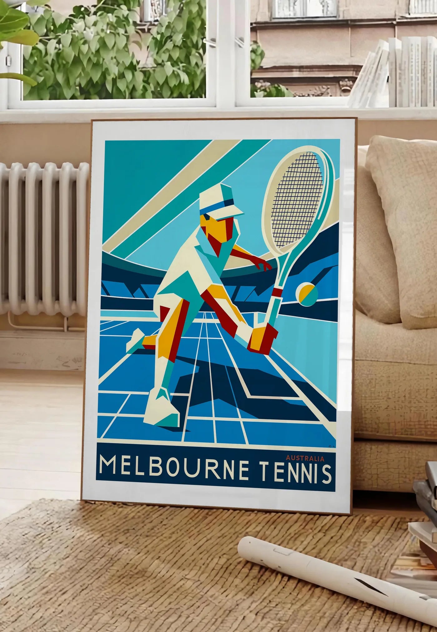 Poster affiche tennis Melbourne Art Deco, posee au sol dans un salon parisien, devant une grande fenetre donnant sur un immeuble haussmannien, entre un ficus et un canape creme
