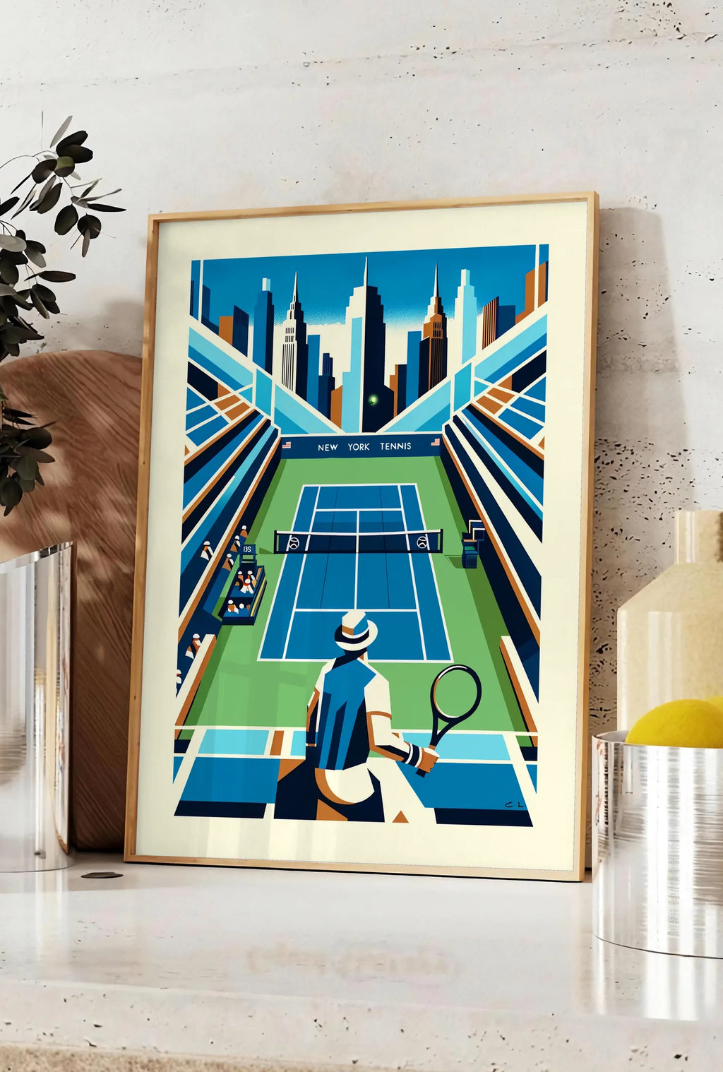 Affiche court de tennis de stade et joueur, posee sur un plan de travail de cuisine en pierre claire, entre une branche d'eucalyptus en vase et un bocal de citrons
