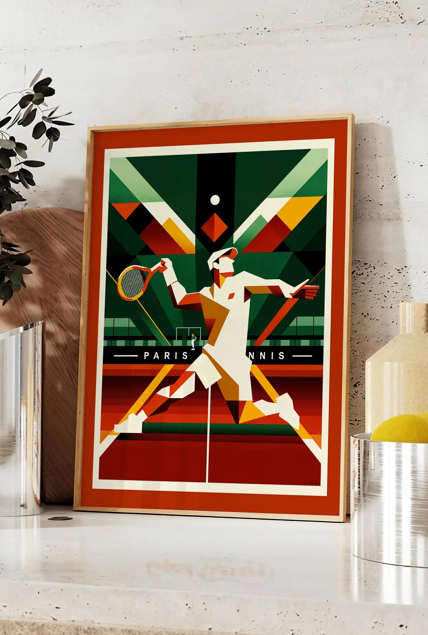 Affiche joueur de tennis cubiste a la raquette, posee sur un plan de travail de cuisine en pierre claire, entre une branche d'eucalyptus en vase et un bocal de citrons