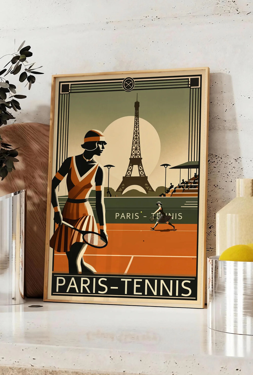 Affiche joueuse de tennis 1920 et raquette, posee sur un plan de travail de cuisine en pierre claire, entre une branche d'eucalyptus en vase et un bocal de citrons