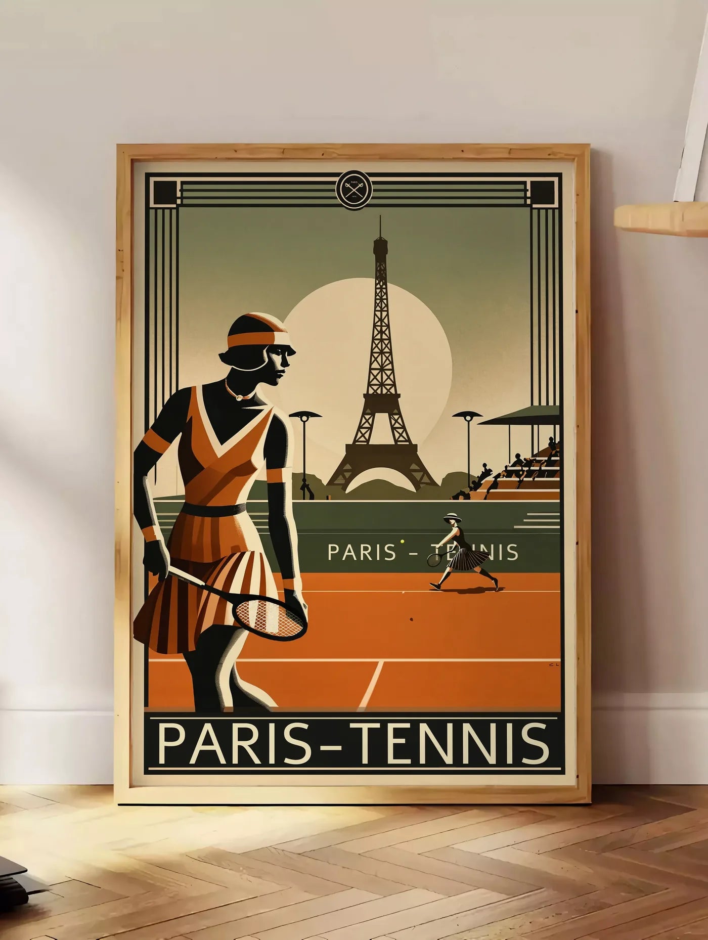 Estampe joueuse de tennis 1920 et raquette, posee au sol dans un coin salon, sur un parquet a chevrons, pres d'une table d'appoint en chene chargee de livres