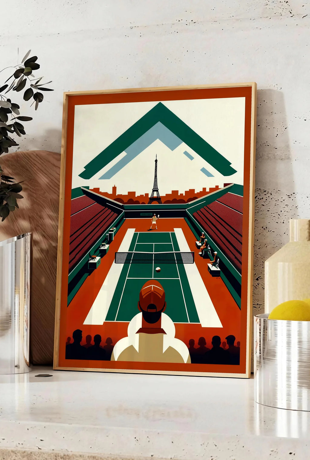 Affiche court de tennis vu d'en haut et spectateur, posee sur un plan de travail de cuisine en pierre claire, entre une branche d'eucalyptus en vase et un bocal de citrons