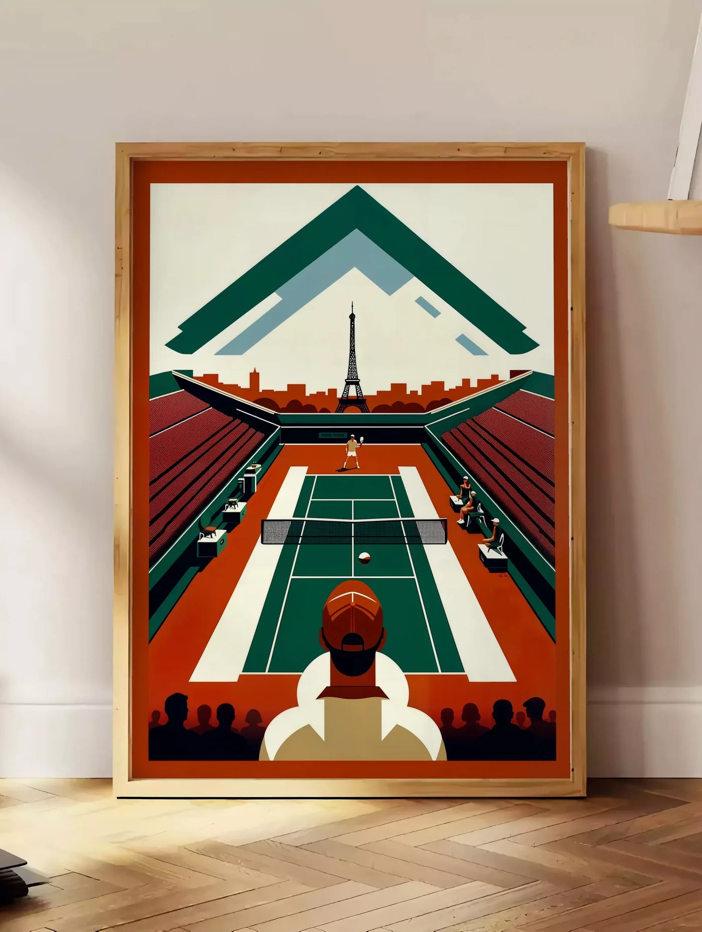 Estampe court de tennis vu d'en haut et spectateur, posee au sol dans un coin salon, sur un parquet a chevrons, pres d'une table d'appoint en chene chargee de livres