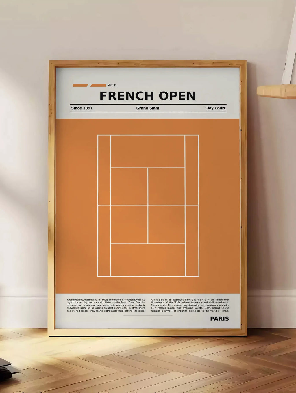 Estampe court de tennis stylisé en terre battue avec titre FRENCH OPEN, posee au sol dans un coin salon, sur un parquet a chevrons, pres d'une table d'appoint en chene chargee de livres