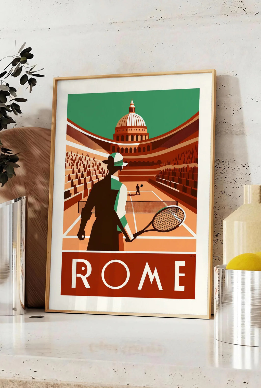 Affiche joueur de tennis de dos et grande coupole, posee sur un plan de travail de cuisine en pierre claire, entre une branche d'eucalyptus en vase et un bocal de citrons