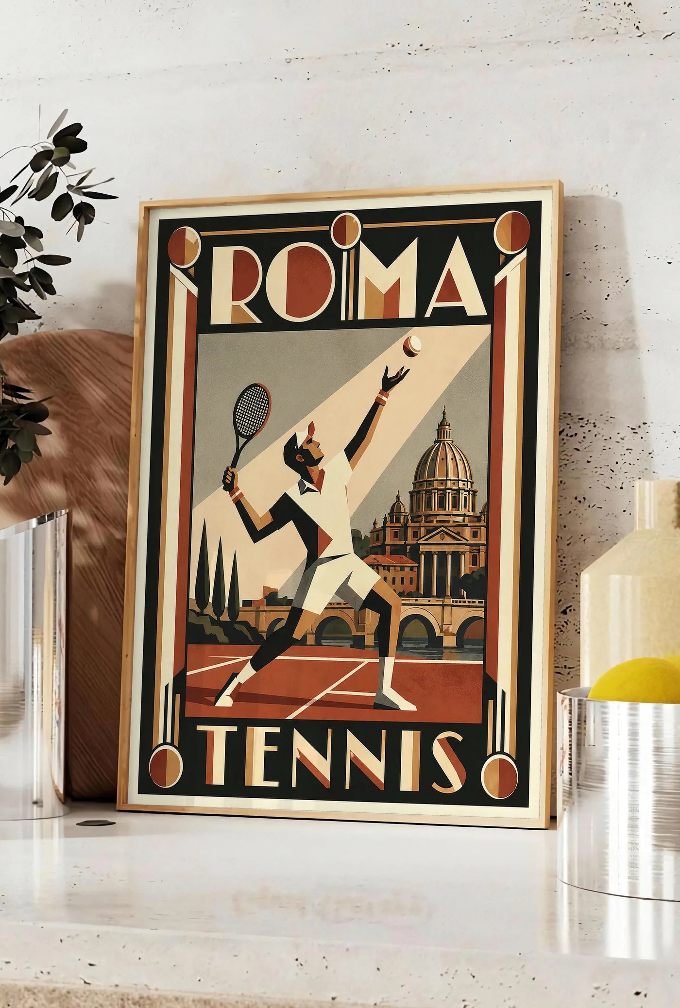 Affiche affiche tennis Rome Art Deco, posee sur un plan de travail de cuisine en pierre claire, entre une branche d'eucalyptus en vase et un bocal de citrons