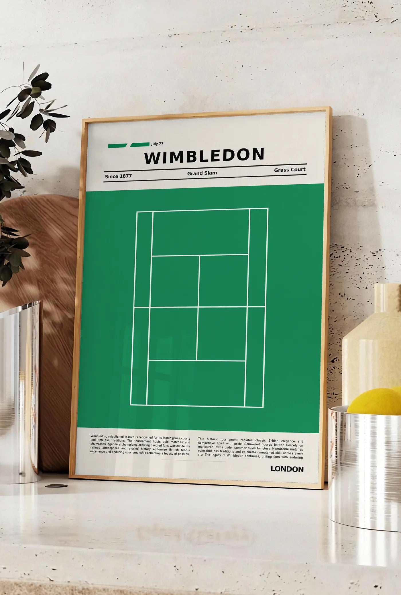 Affiche plan de court de tennis de gazon vert, posee sur un plan de travail de cuisine en pierre claire, entre une branche d'eucalyptus en vase et un bocal de citrons