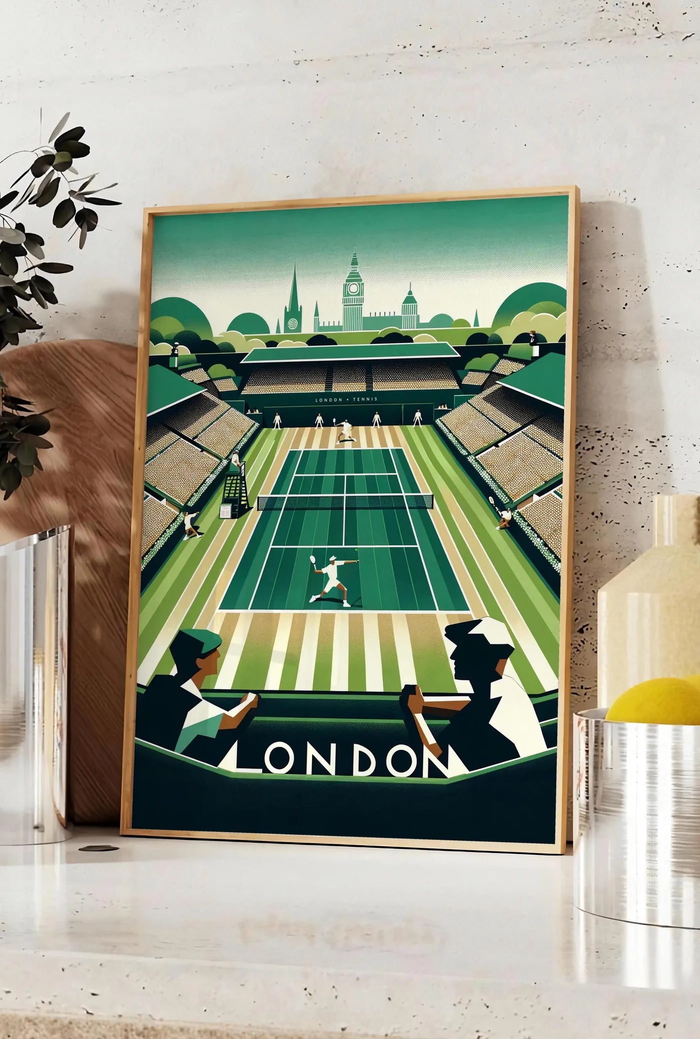 Affiche court de tennis en gazon et spectateurs, posee sur un plan de travail de cuisine en pierre claire, entre une branche d'eucalyptus en vase et un bocal de citrons