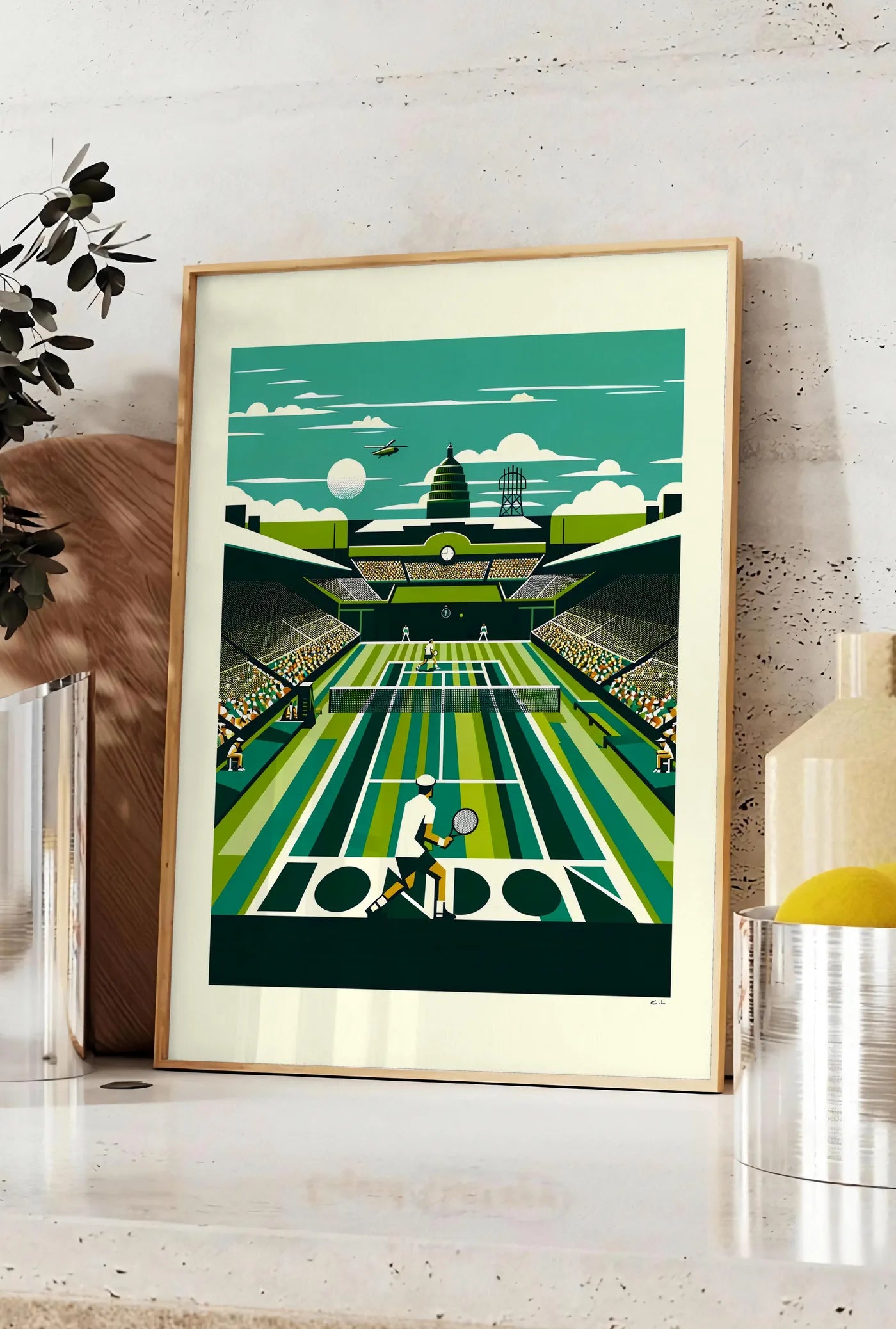 Affiche joueur de tennis de dos sur gazon raye, posee sur un plan de travail de cuisine en pierre claire, entre une branche d'eucalyptus en vase et un bocal de citrons