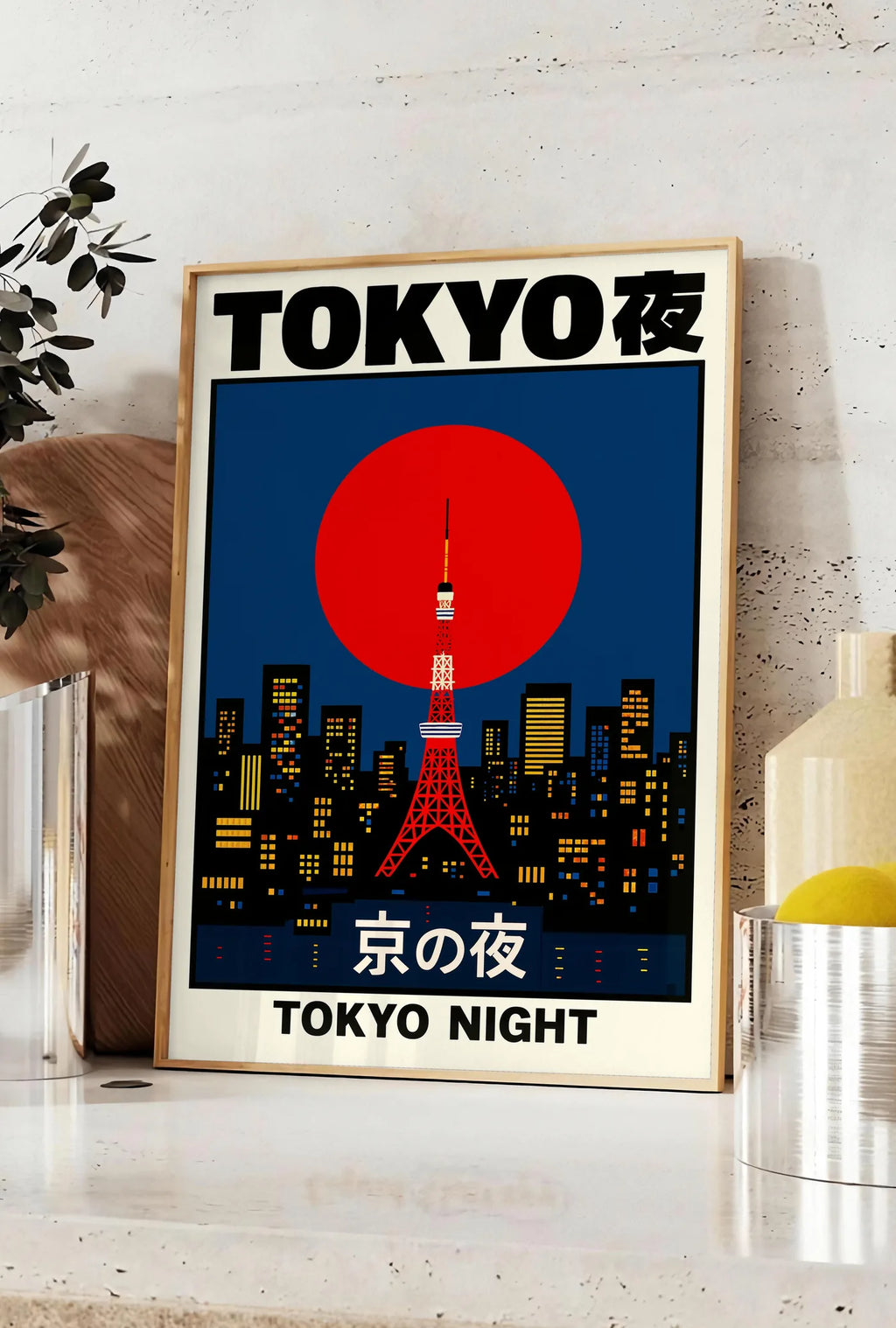 Affiche affiche tour de Tokyo et soleil rouge art japonais, posee sur un plan de travail de cuisine en pierre claire, entre une branche d'eucalyptus en vase et un bocal de citrons